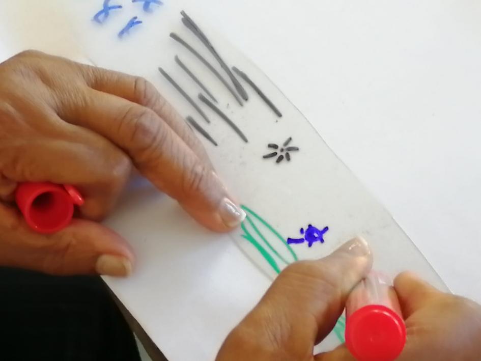 Dos manos dibujando líneas y estrellas sobre un retazo de plástico