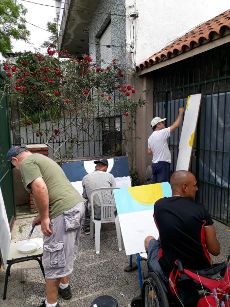 Taller Muralismo 4 personas cada una pintando un fragmento de mural colectivo