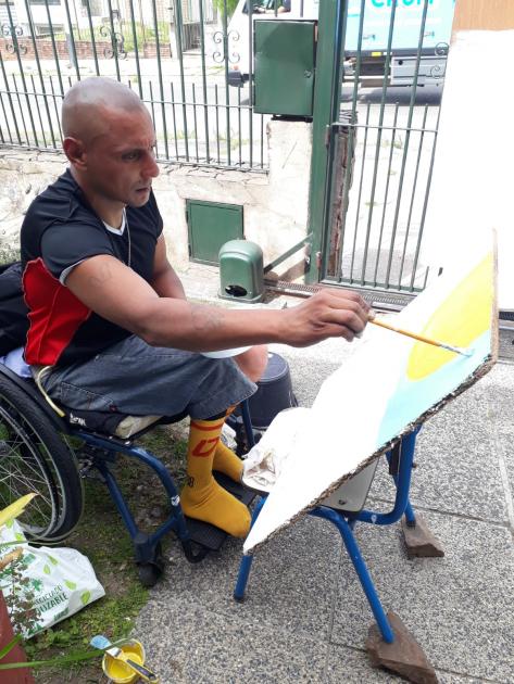 Taller Muralismo Persona en silla de ruedas pintando un fragmento de mural colectivo
