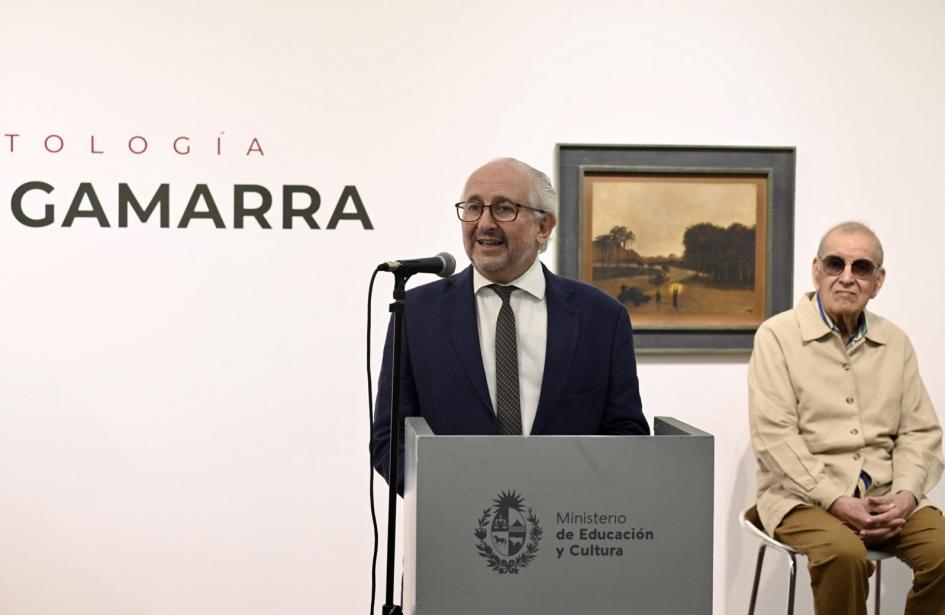 Ministro Pablo da Silveira. Persona hablando frente a atril y otra persona sentada al fondo.