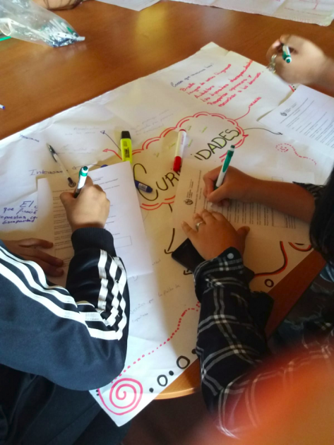 Adolescentes expresando sus conclusiones de distintas maneras en un papelógrafo