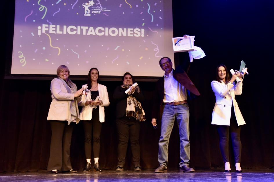 Ceremonia del Premio ReachingU al docente uruguayo 2022 Persona levantando su premio mientras quienes le rodean aplauden