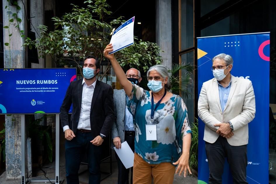 Autoridades sonriendo y una participantes con un brazo levantado mostrando el certificado