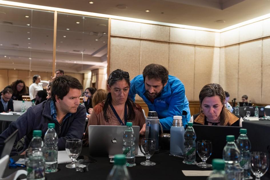 Personas juntas en una mesa mirando una laptop