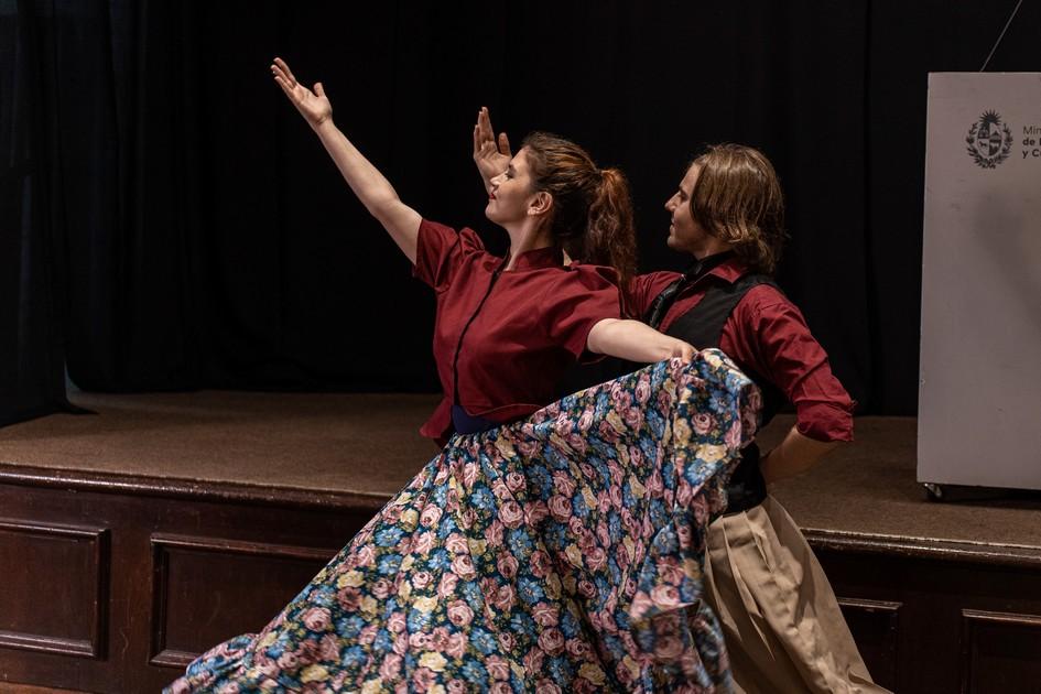 Dos personas con atuendos antiguos realizando danzas folclóricas