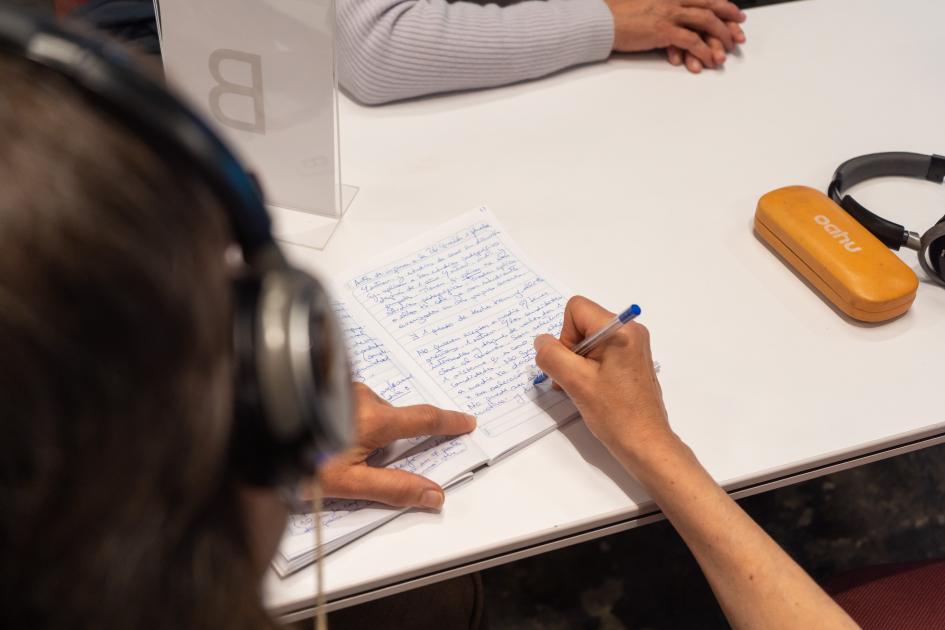 Mujer con auriculares escribiendo en un papel
