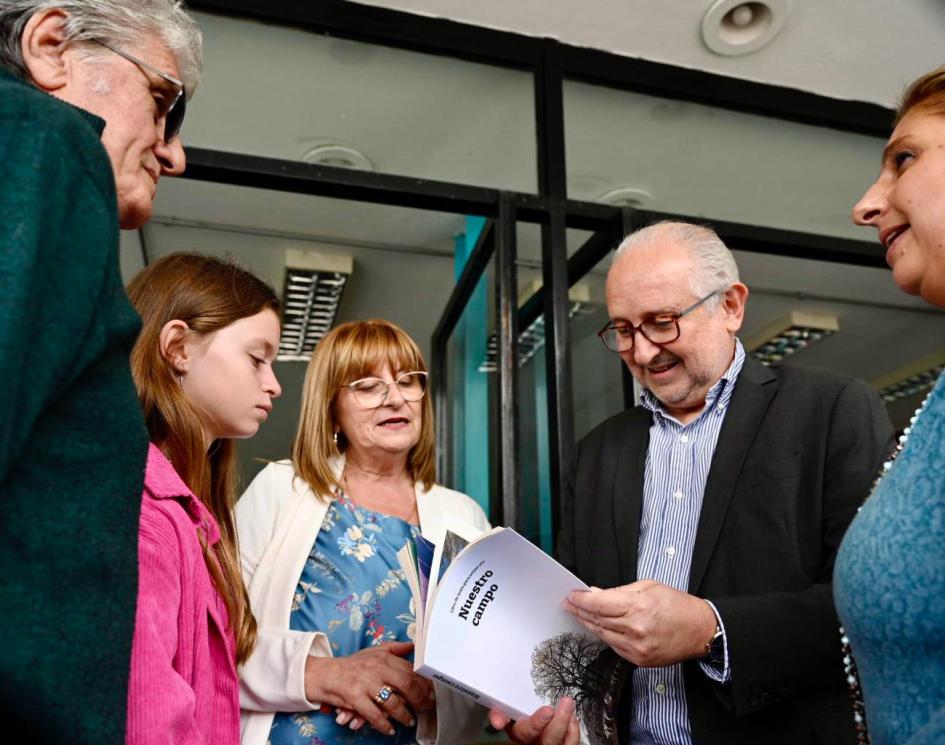 Ministro entregó tres ejemplares de "Nuestro campo" para la biblioteca del liceo. Personas paradas hablando.