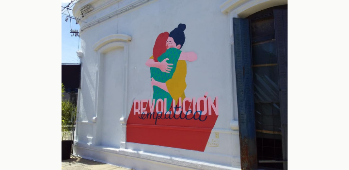 Ellas en Marzo, "Pintan las pibas" en Paysandú. Mural que ilustra dos mujeres dándose un abrazo con la palabra revolución.