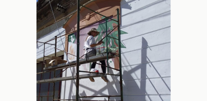 Ellas en Marzo, "Pintan las pibas" en Paysandú. Artista sentada en un andamio