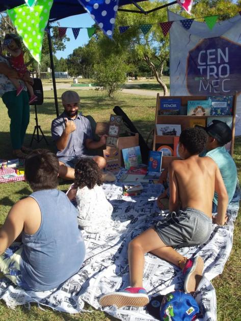 Adulto leyendo y niños y niña escuchando