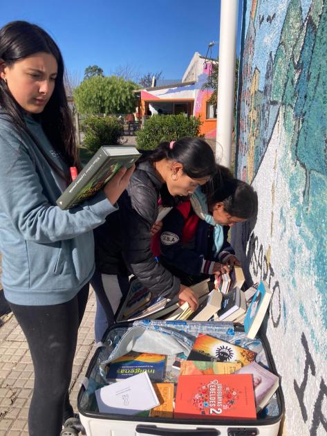 Personas revisando una maleta con libros.