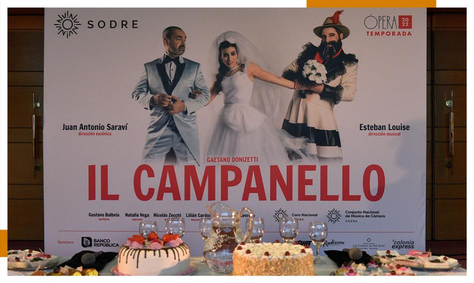 Parte de la escenografía de Il Campanello En el fondo está el banner de la ópera y adelante hay una mesas con tortas dulces