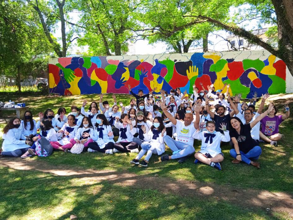 Escolares y referentes del proyecto con el muro realizado. En la imagen aparece el grupo escolar junto a referentes del proyecto. Atrás el muro realizado.