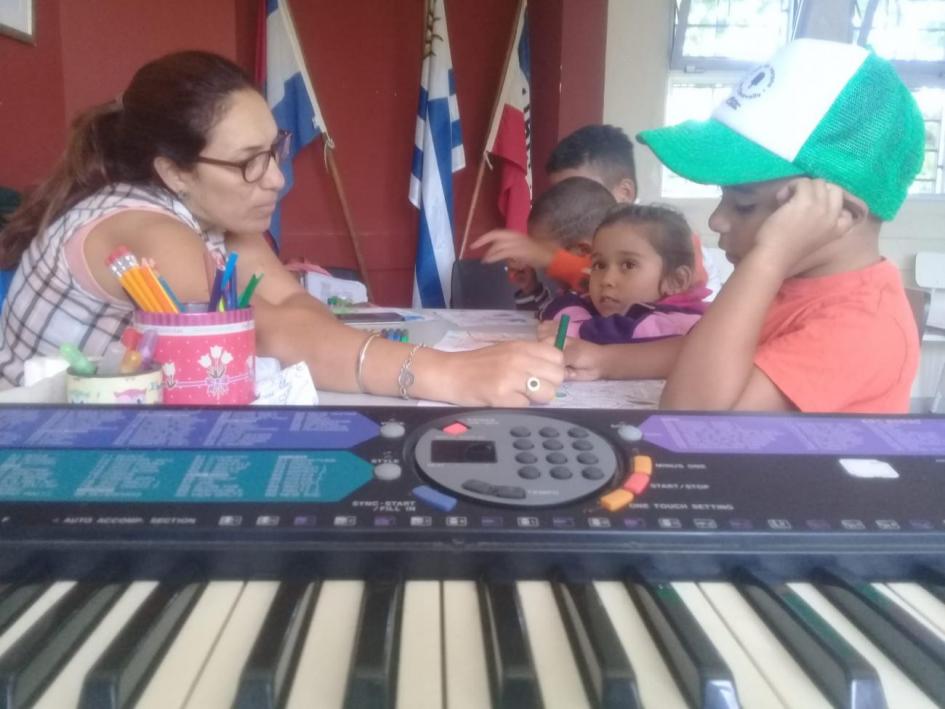 Niños y niñas junto a la tallerista, participando del taller de música