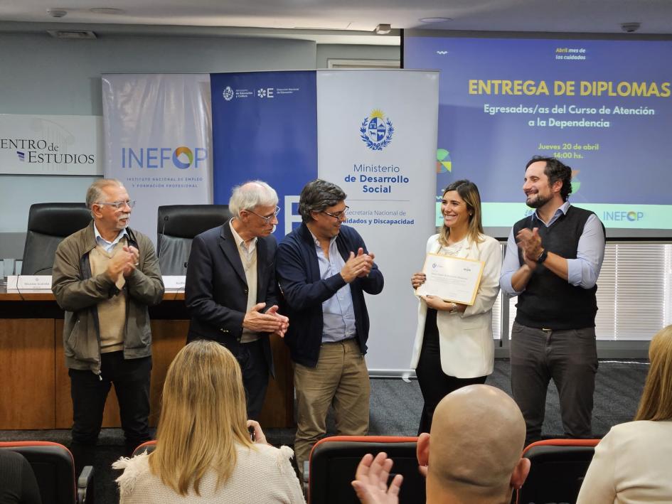 Egresada recibiendo el diploma de parte de las autoridades presentes