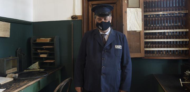 Señor parado dentro de la estación donde están los elementos de época del ferrocarril