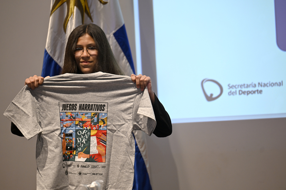 Estudiante sosteniendo una camiseta de Juegos Narrativos 2026
