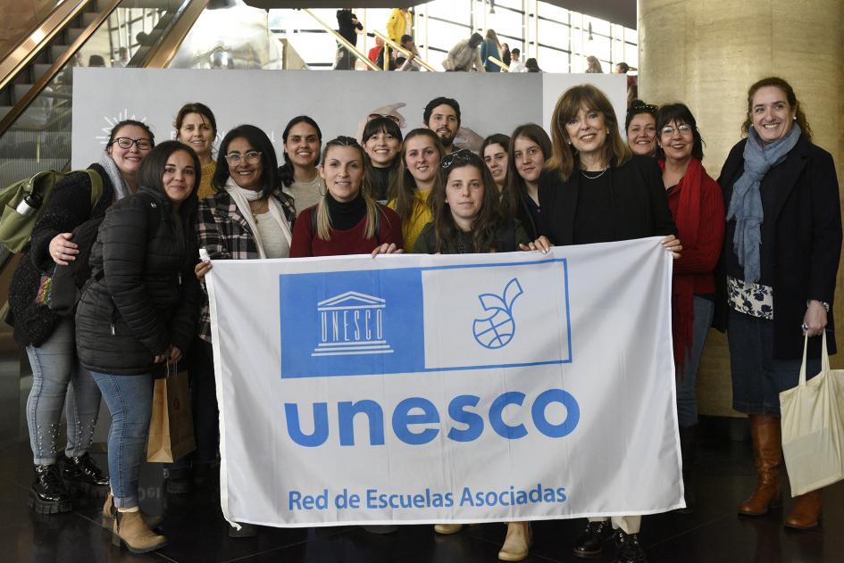 Personas jóvenes y adultas con una bandera que dice Unesco