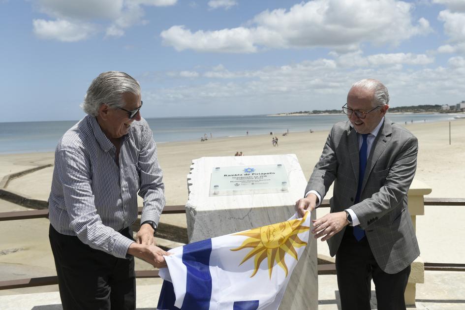 Autoridades con la bandera uruguayo en la mano, descubriendo la placa