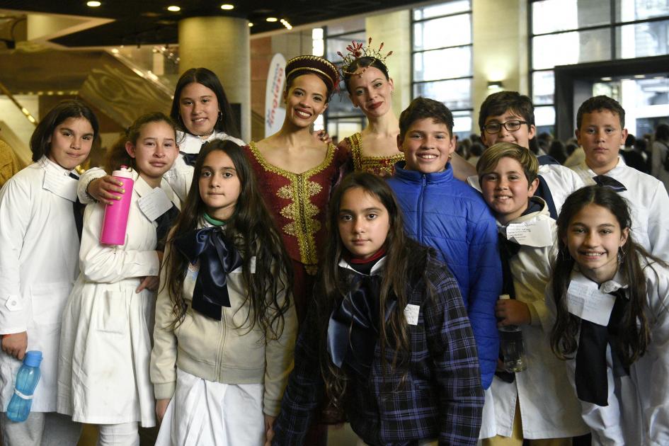 Niños con su uniforme escolar posando para una foto con actores del ballet