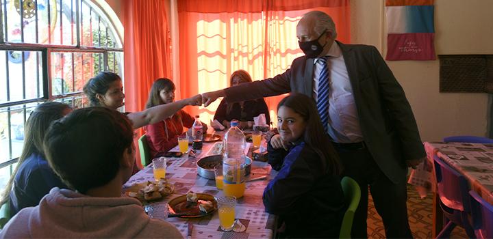 Ministro del MEC saludando a personas Ministro del MEC saludando con puño a personas que están sentadas en una mesa