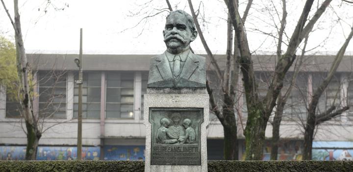 Escultura de Felipe Sanguinetti con la escuela de fondo