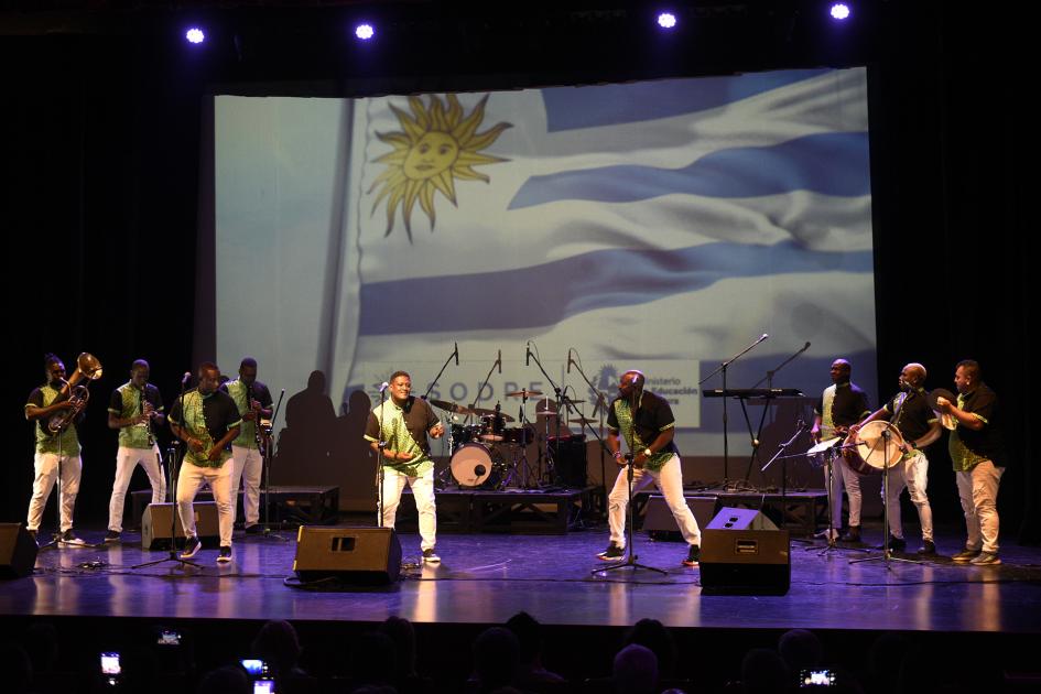 Personas tocando instrumentos y bailando en escenario.