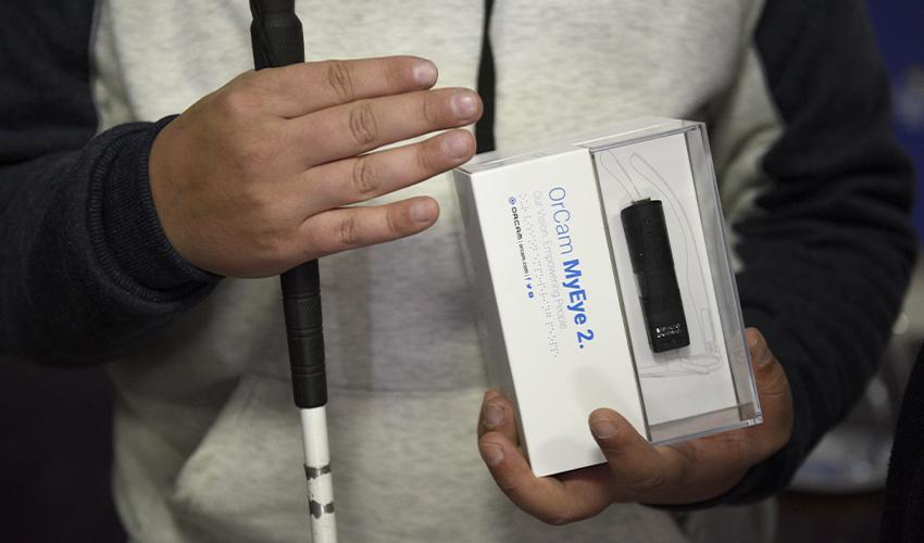 Dispositivo OrCam en manos de un beneficiario Dispositivo OrCam en manos de un beneficiario