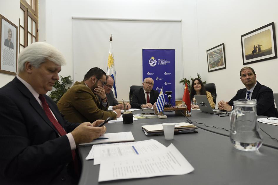 Personas sentadas en mesa con bandera y roll up MEC en el fondo.