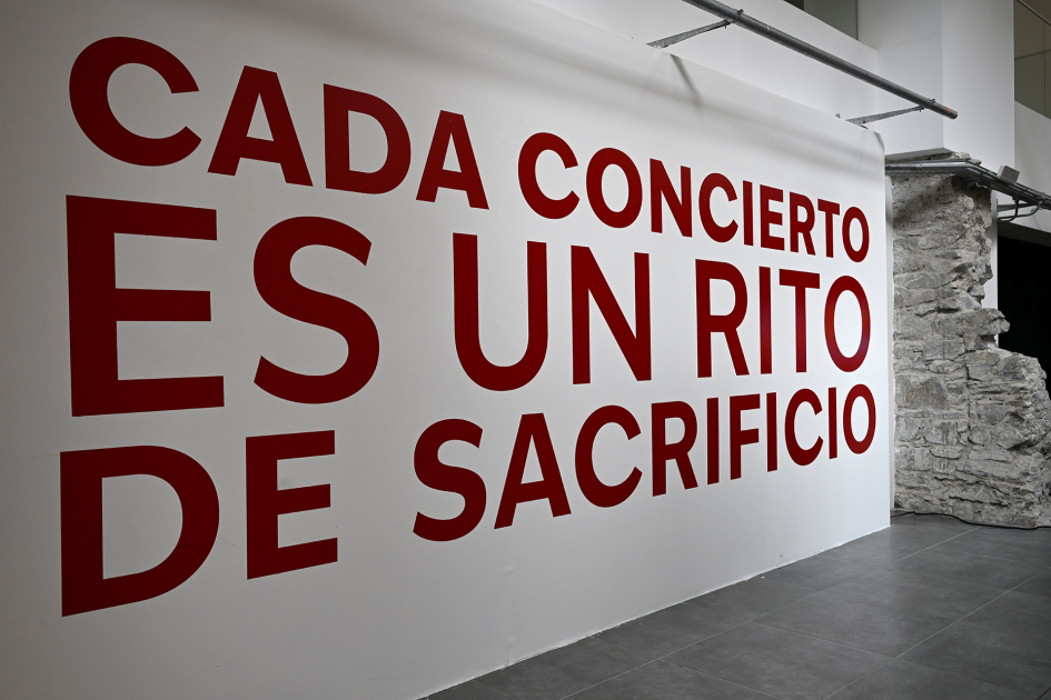 Pared blanca, con el texto "Cada concierto es un rito de Sacrificio"