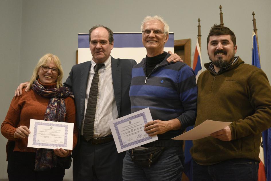 Personas paradas con diplomas en mano.