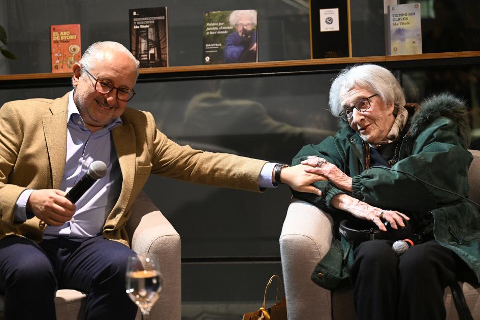 Plano del ministro Pablo da Silveira y la poeta Ida Vitale en la celebración, sentados lado a lado.