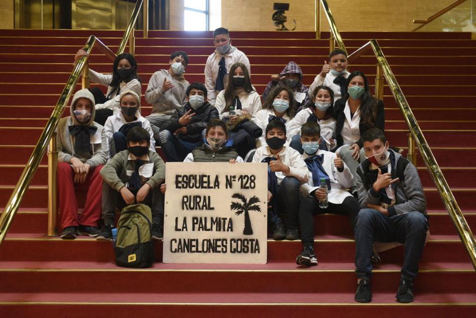 Alumnos con cartel de su escuela posando en la escalera del Sodre