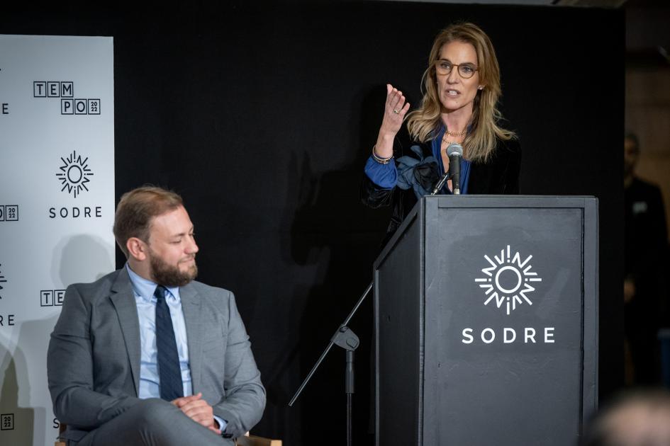 Presidenta del Sodre, Adela Dubra Mujer hablando atrás de un atril y a la izquierda hay un hombre sentado