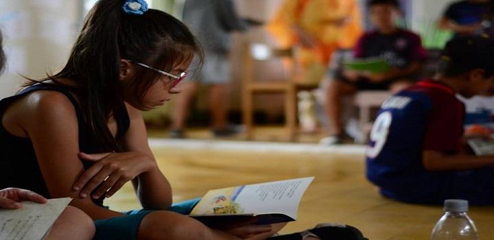 Niña en biblioteca de verano en Treinta y Tres Niña con libro leyendo