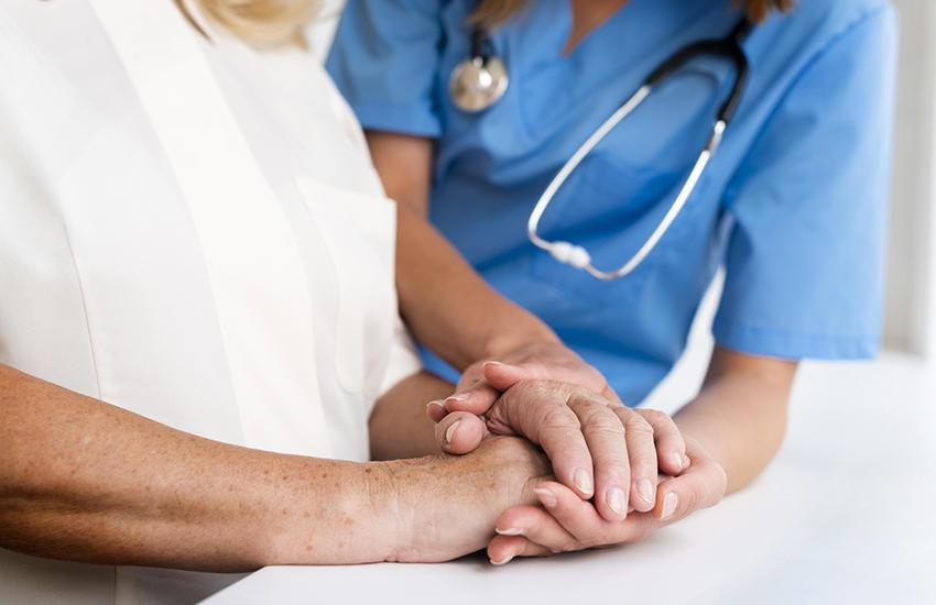 Enfermera tomando la mano de persona adulta mayor