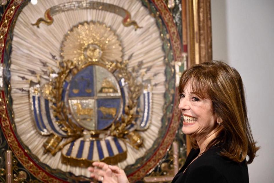 Persona sonriendo frente a un escudo.