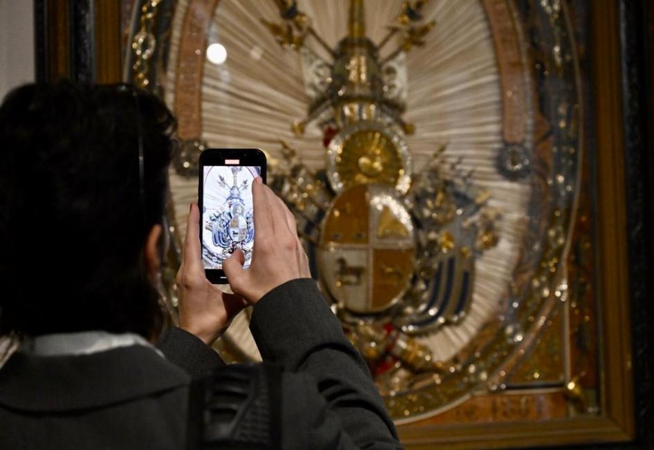 La exposición pone en relieve el valor patrimonial de los escudos nacionales. Persona sacando foto a un escudo.