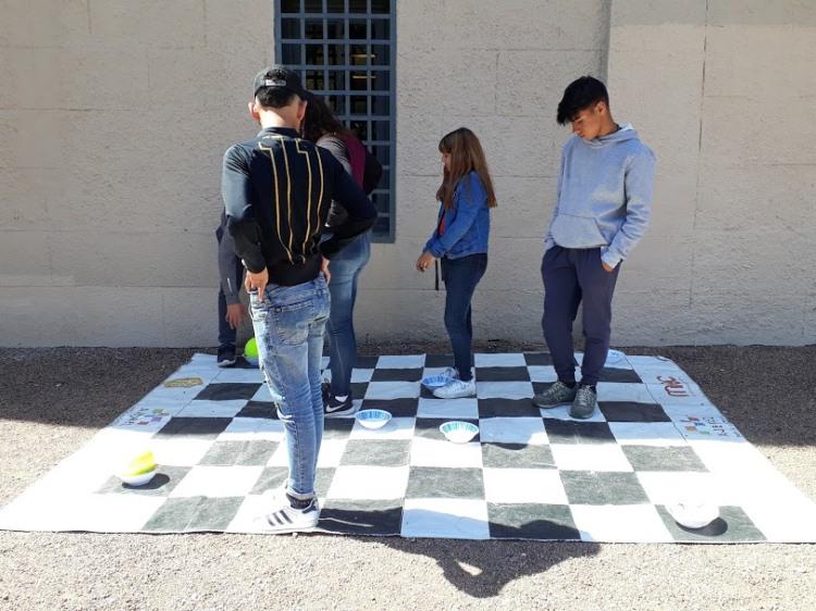 Jóvenes jugando sobre el tablero de ajedrez a dinámica recreativa con pelotas. tablero grande de ajedrez, jovenes parados sobre él