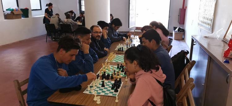 Mesa con cuatro tableros de ajedrez y jóvenes jugando