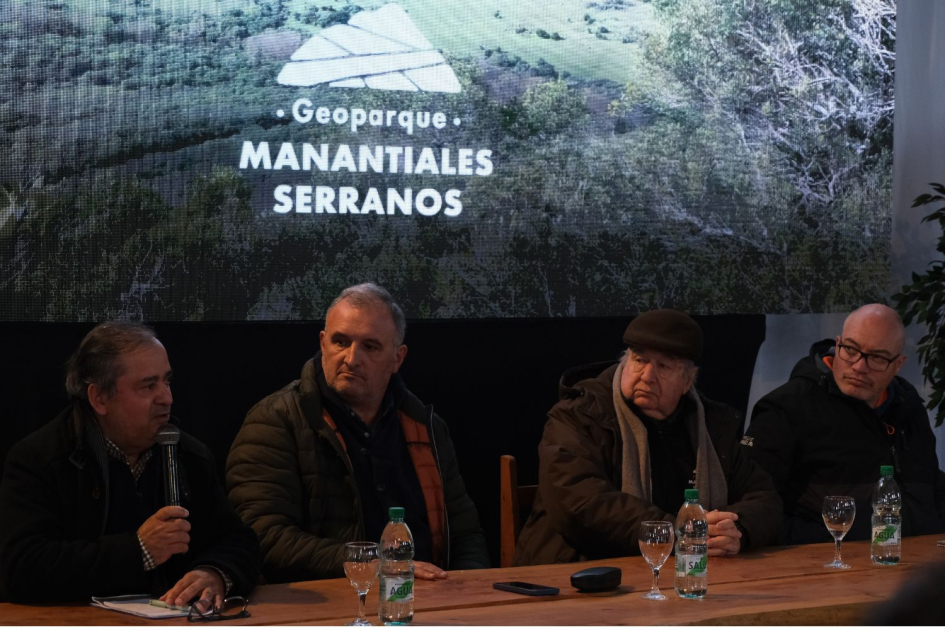 Geoparque Manantiales Serranos 4 personas sentadas a la mesa, fondo logo de Geoparque Manantiales Serranos
