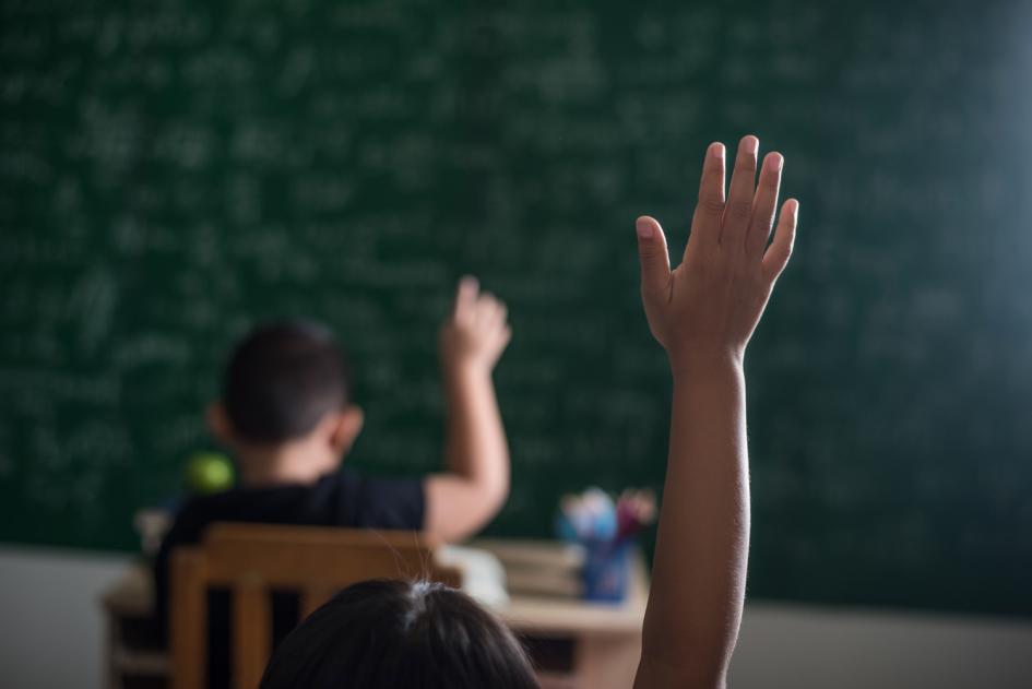 Foto ilustrativa. Niño levantando la mano en un salón de clases