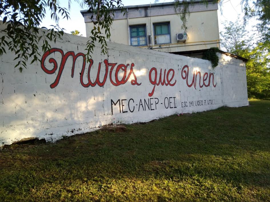 Imagen del mural que da nombre al proyecto: Muros que unen Imagen del mural con la leyenda "Muros que unen - MEC - ANEP - OEI - Esc. 140, Liceo 7, UTU"