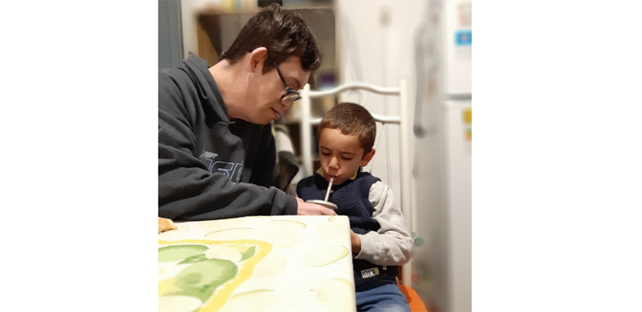 Niño toma mate mientras un mayor lo ayuda a sostener el mate