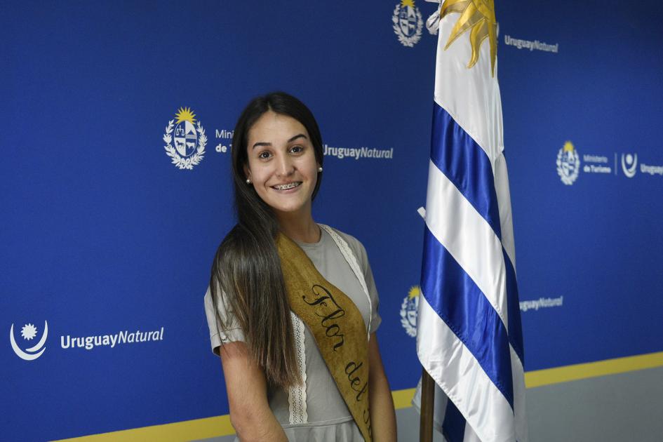 Mujer posando con la bandera uruguaya al fondo