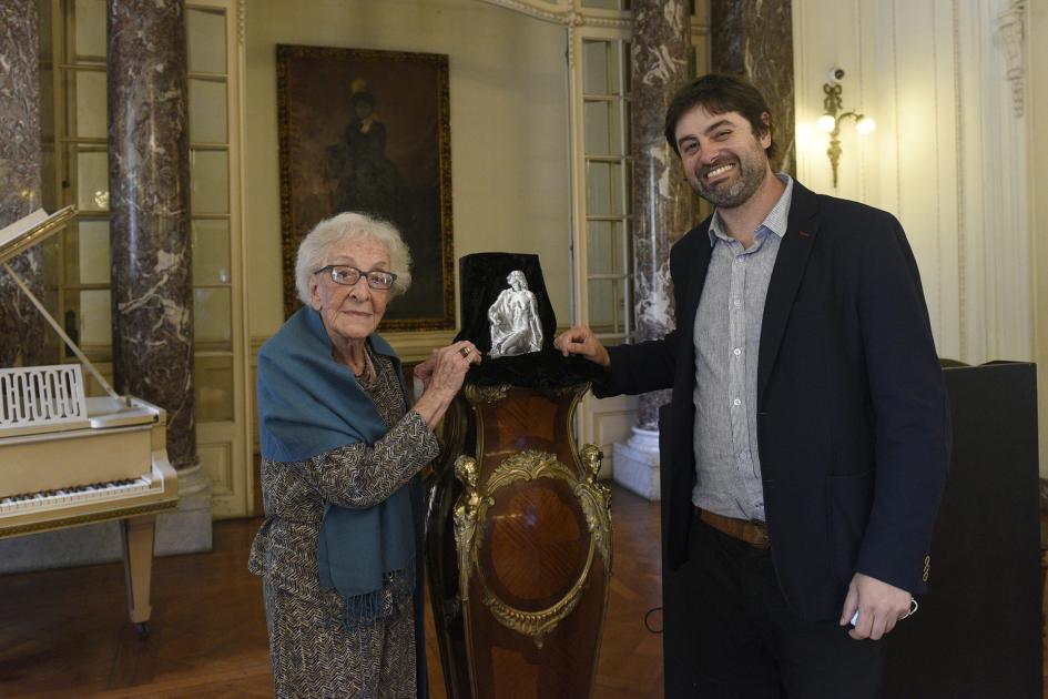 Personas paradas junto a la estatuilla