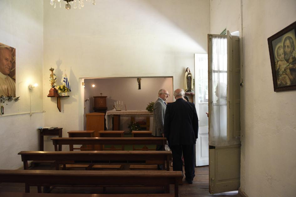 Vista general de una capilla y de costado se ve a dos hombre