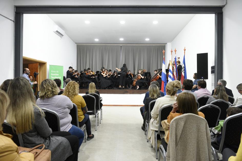 Vista de la sala con gente y en el escenario está la la Orquesta Juvenil del Sodre, núcleo Dolores