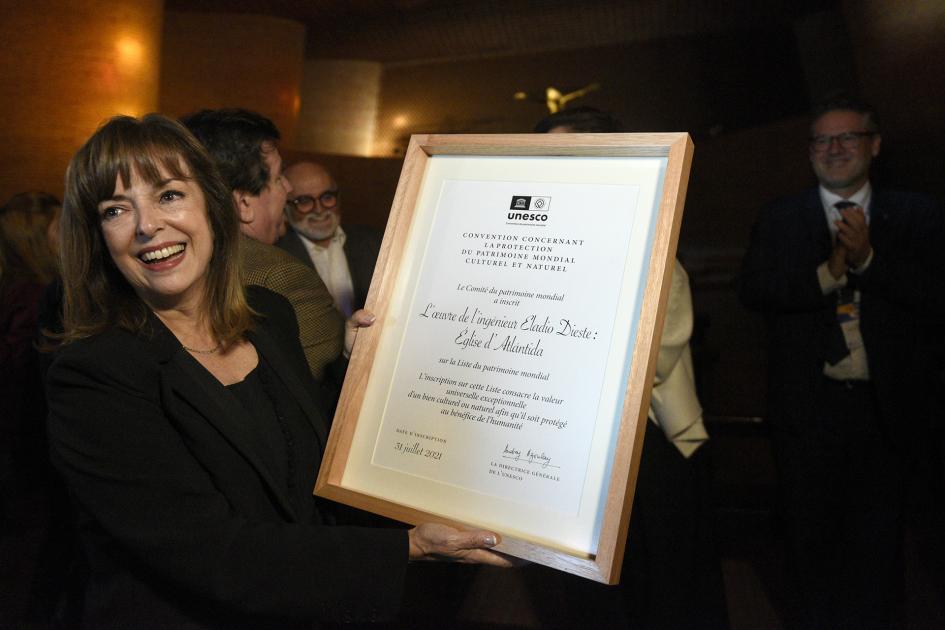 Mujer de negro con el certificado en mano y sonriendo