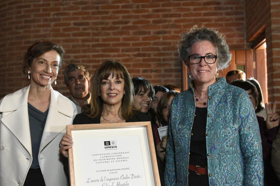 Tres mujeres y la del medio está con el certificado en la mano